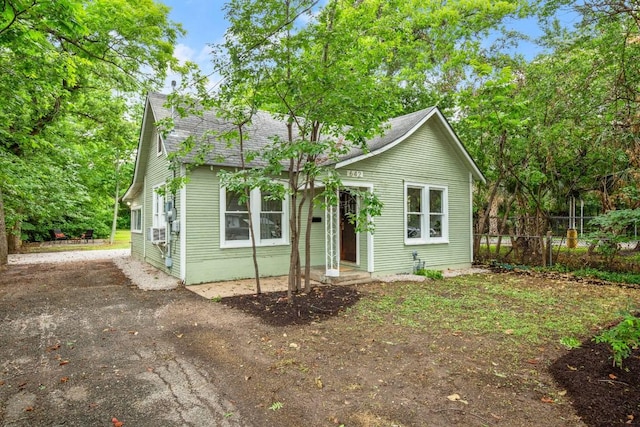 bungalow featuring fence, a shingled roof, and aphalt driveway