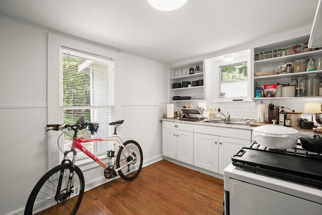 kitchen with open shelves, white range with gas stovetop, tasteful backsplash, a sink, and dark wood finished floors