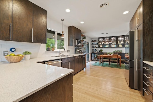 1712 Mccoy Pl, Georgetown, TX 78626 - kitchen with dark brown cabinetry, light wood finished floors, tasteful backsplash, pendant lighting, and recessed lighting
