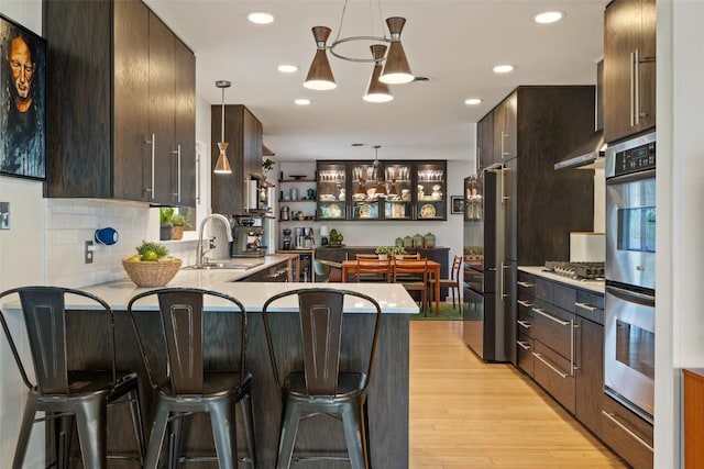 1712 Mccoy Pl, Georgetown, TX 78626 - kitchen with a sink, a peninsula, decorative backsplash, a kitchen bar, and dark brown cabinets