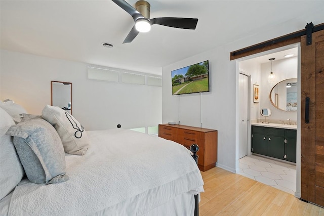 1712 Mccoy Pl, Georgetown, TX 78626 - bedroom with a barn door, light wood-type flooring, a ceiling fan, and ensuite bathroom
