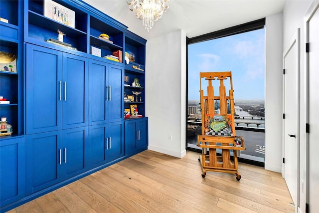 game room with light wood-type flooring, baseboards, and a notable chandelier