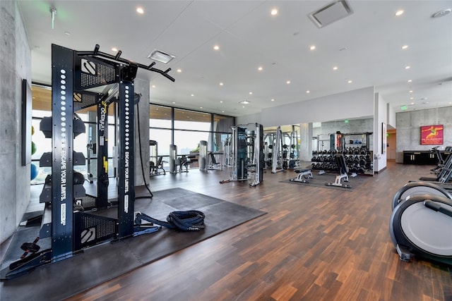 workout area featuring visible vents, recessed lighting, wood finished floors, and a wall of windows
