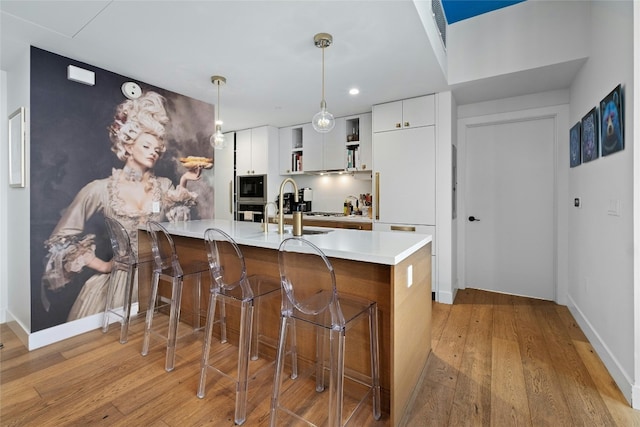 kitchen with light countertops, a breakfast bar, built in microwave, and light wood finished floors