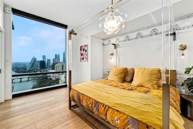 bedroom with a view of city, floor to ceiling windows, and wood finished floors
