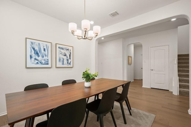 1625 Stinnett Dr, Leander, TX 78641 - dining space featuring a notable chandelier, light wood finished floors, arched walkways, stairs, and visible vents