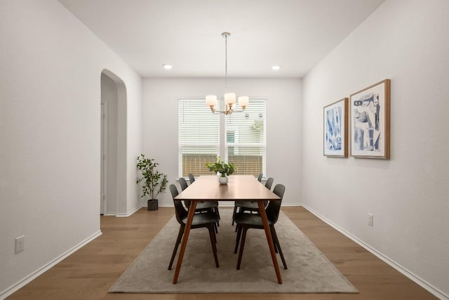 1625 Stinnett Dr, Leander, TX 78641 - dining space featuring arched walkways, baseboards, a chandelier, and wood finished floors