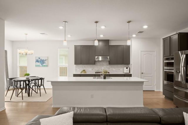 1625 Stinnett Dr, Leander, TX 78641 - kitchen featuring stainless steel fridge, light countertops, backsplash, under cabinet range hood, and visible vents