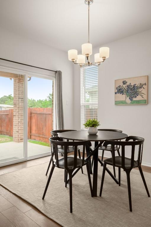 1625 Stinnett Dr, Leander, TX 78641 - dining area with a notable chandelier, wood finished floors, and a healthy amount of sunlight