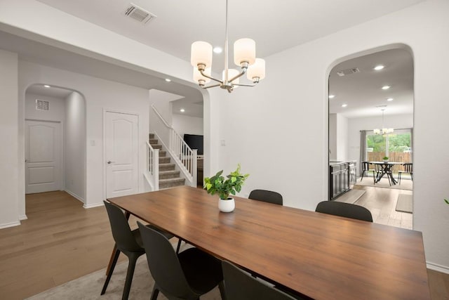 1625 Stinnett Dr, Leander, TX 78641 - dining area with visible vents, arched walkways, stairway, light wood finished floors, and a chandelier