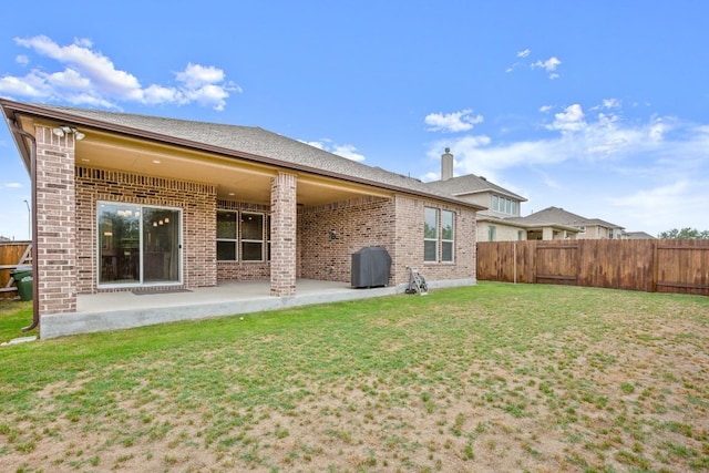 1625 Stinnett Dr, Leander, TX 78641 - rear view of property featuring a fenced backyard, a patio, a lawn, and brick siding