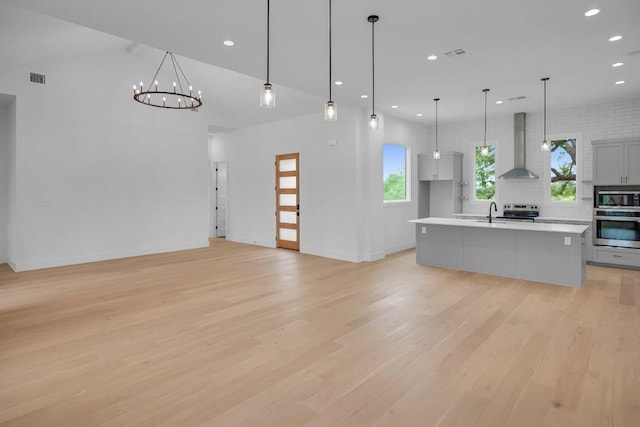 309 Alabaster, Horseshoe Bay, TX 78657 - kitchen featuring wall chimney range hood, plenty of natural light, appliances with stainless steel finishes, light countertops, and light wood-style floors