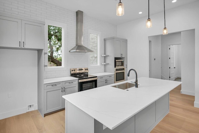309 Alabaster, Horseshoe Bay, TX 78657 - kitchen featuring wall chimney range hood, appliances with stainless steel finishes, a sink, gray cabinets, and decorative backsplash