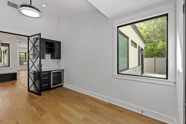 spare room with visible vents, baseboards, beverage cooler, recessed lighting, and light wood-style flooring