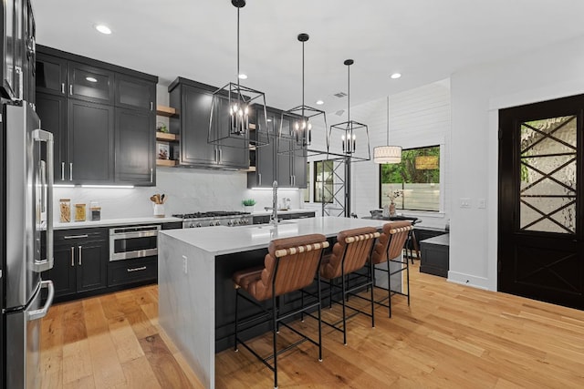 408 W 34th St, Austin, TX 78705 - kitchen featuring stainless steel appliances, light wood-style flooring, dark cabinetry, light countertops, and recessed lighting
