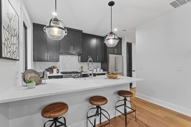 408 W 34th St, Austin, TX 78705 - kitchen with fridge, dark cabinetry, a peninsula, a breakfast bar area, and recessed lighting