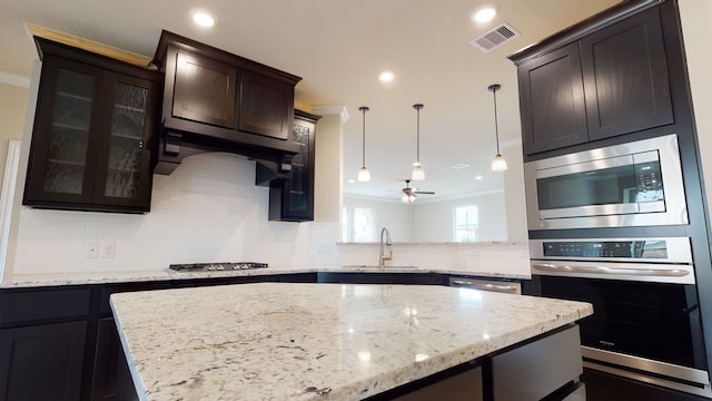 kitchen featuring visible vents, glass insert cabinets, tasteful backsplash, a sink, and stainless steel appliances
