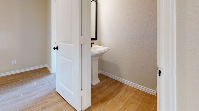 bathroom featuring baseboards, a textured wall, and wood finished floors