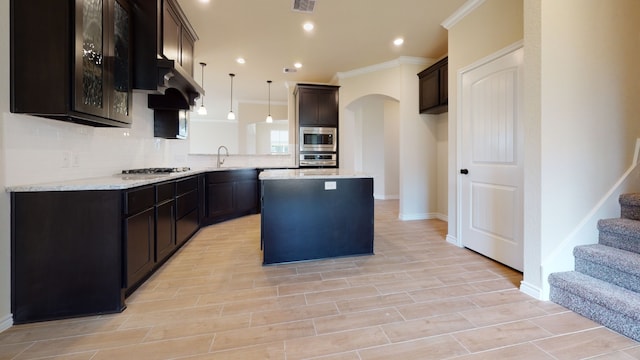 kitchen featuring ornamental molding, a kitchen island, a sink, backsplash, and stainless steel appliances