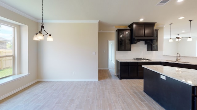 kitchen with stainless steel gas stovetop, hanging light fixtures, a sink, and visible vents