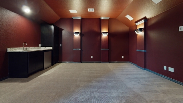 home theater with visible vents, light carpet, baseboards, a sink, and vaulted ceiling