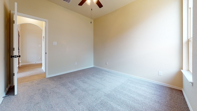 unfurnished room with visible vents, a ceiling fan, carpet flooring, baseboards, and arched walkways