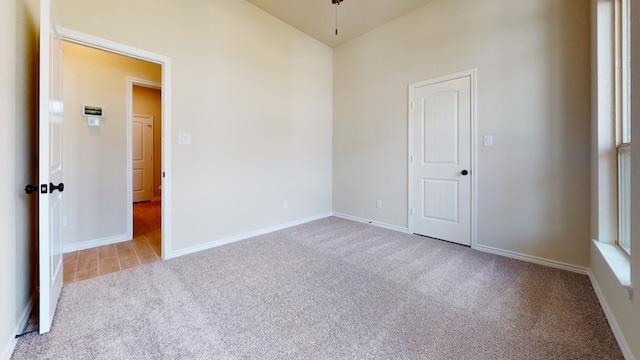 unfurnished room with baseboards, carpet, and vaulted ceiling