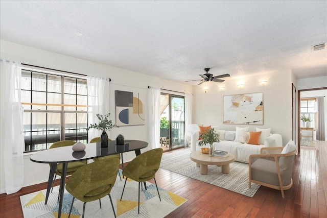 living room with ceiling fan, hardwood / wood-style flooring, a textured ceiling, and visible vents