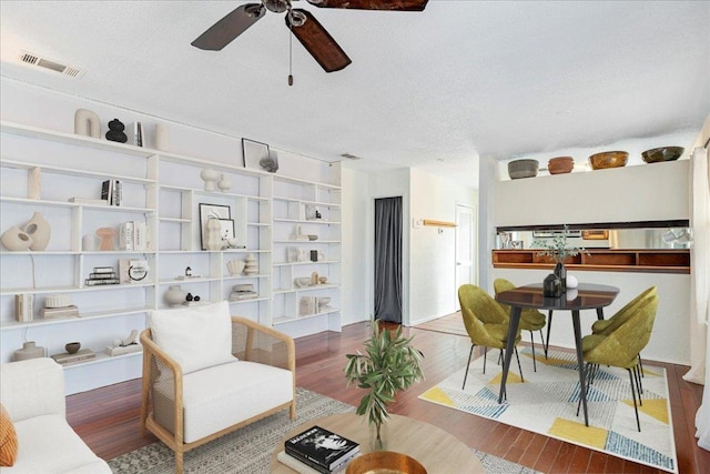 sitting room with visible vents, a textured ceiling, ceiling fan, and wood finished floors