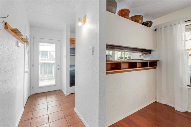 kitchen with baseboards, a textured ceiling, and a textured wall
