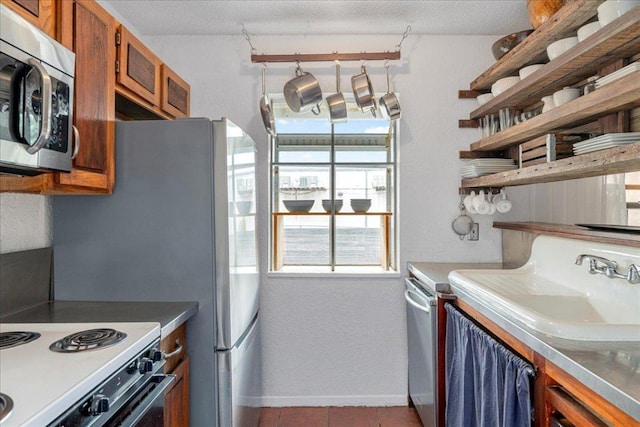 kitchen with open shelves, stainless steel microwave, brown cabinetry, and a sink