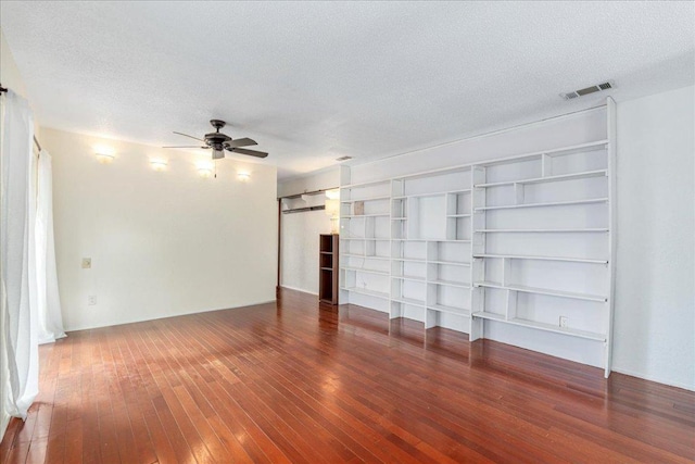 unfurnished living room with ceiling fan, wood-type flooring, a textured ceiling, and visible vents