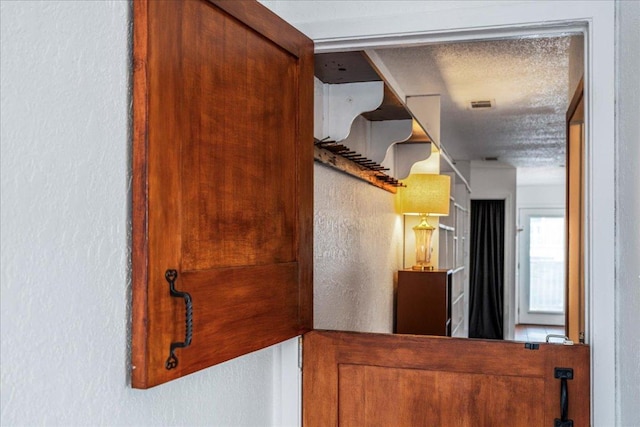 hallway featuring a textured wall and visible vents