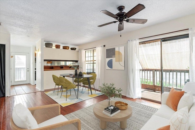 living room featuring a textured ceiling, ceiling fan, and wood finished floors