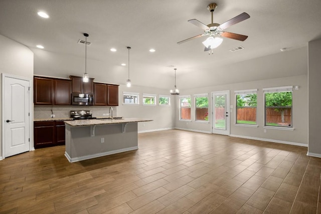 104 N Pasture Cv, Hutto, TX 78634 - kitchen with stainless steel microwave, black electric range, open floor plan, recessed lighting, and ceiling fan