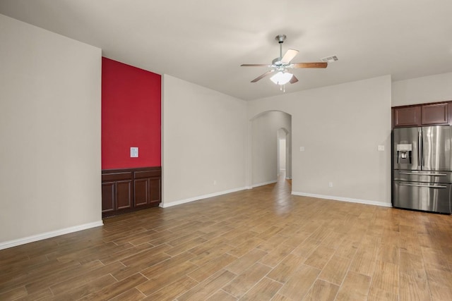 104 N Pasture Cv, Hutto, TX 78634 - unfurnished living room with arched walkways, ceiling fan, light wood-type flooring, and baseboards