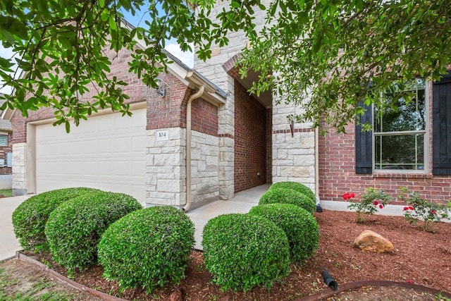 104 N Pasture Cv, Hutto, TX 78634 - view of side of property featuring a garage, stone siding, and brick siding