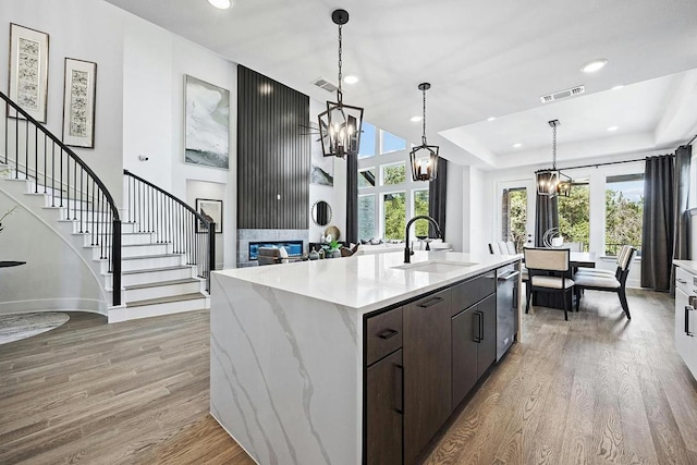 1220 Summer Moon Dr, Georgetown, TX 78628 - kitchen with a chandelier, dishwasher, a fireplace, light wood-style floors, and dark brown cabinetry