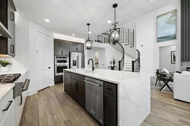 1220 Summer Moon Dr, Georgetown, TX 78628 - kitchen featuring appliances with stainless steel finishes, wood finished floors, recessed lighting, an island with sink, and light stone countertops