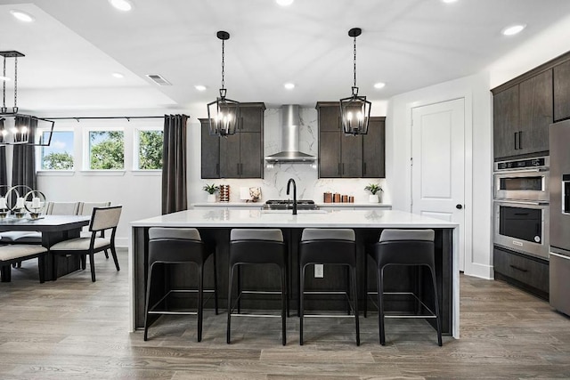 1220 Summer Moon Dr, Georgetown, TX 78628 - kitchen with wall chimney range hood, light countertops, a kitchen breakfast bar, recessed lighting, and decorative backsplash
