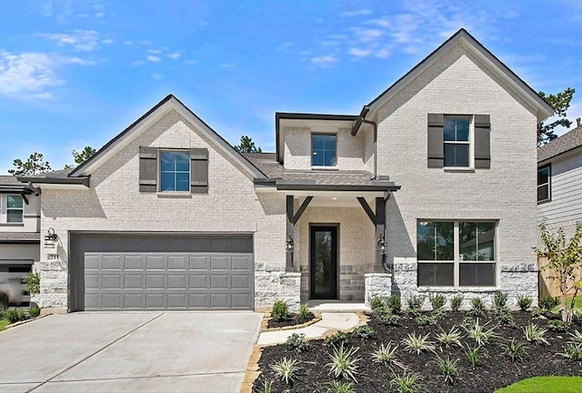 view of front of property with an attached garage, brick siding, driveway, and stone siding