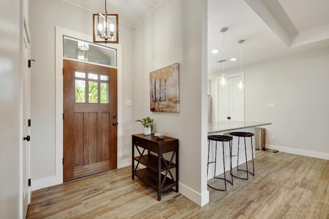 entryway with baseboards, a notable chandelier, and light wood-type flooring