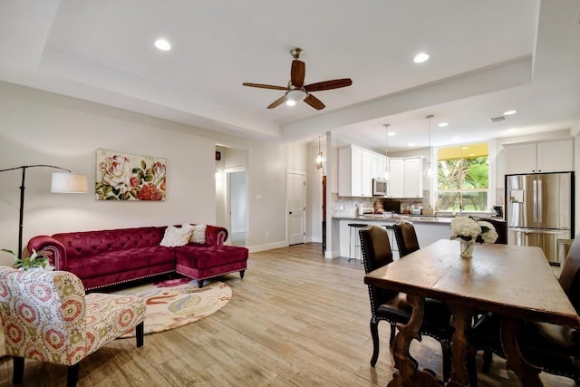 living area with recessed lighting, a tray ceiling, and ceiling fan