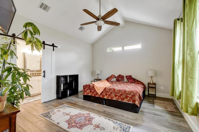 bedroom with visible vents, a barn door, vaulted ceiling with beams, and light wood-type flooring