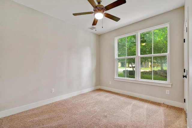 empty room with baseboards, ceiling fan, carpet, and visible vents