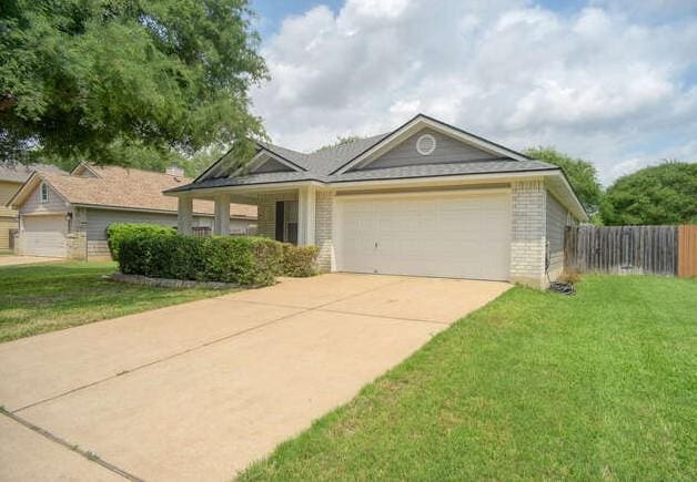 ranch-style home with driveway, a front yard, a garage, brick siding, and fence