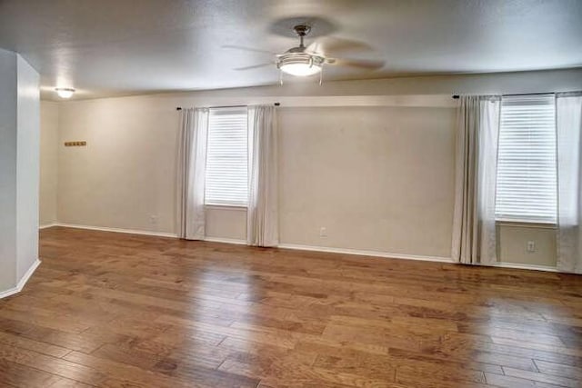 empty room with a healthy amount of sunlight, wood-type flooring, and a ceiling fan