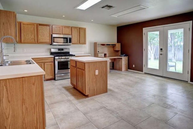 kitchen featuring french doors, a center island, a sink, light countertops, and stainless steel appliances