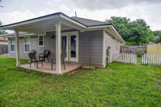 rear view of house with a lawn and fence