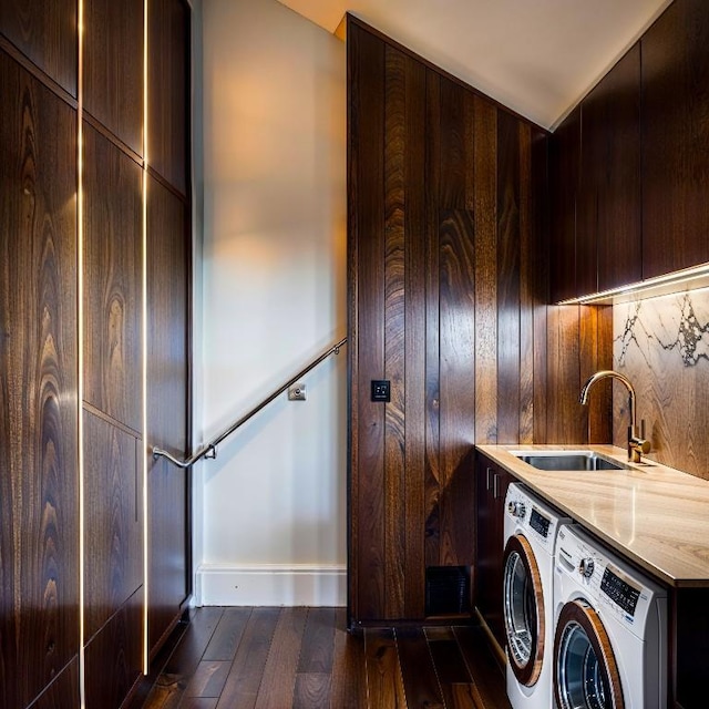 washroom with baseboards, a sink, dark wood-style floors, and washer and clothes dryer